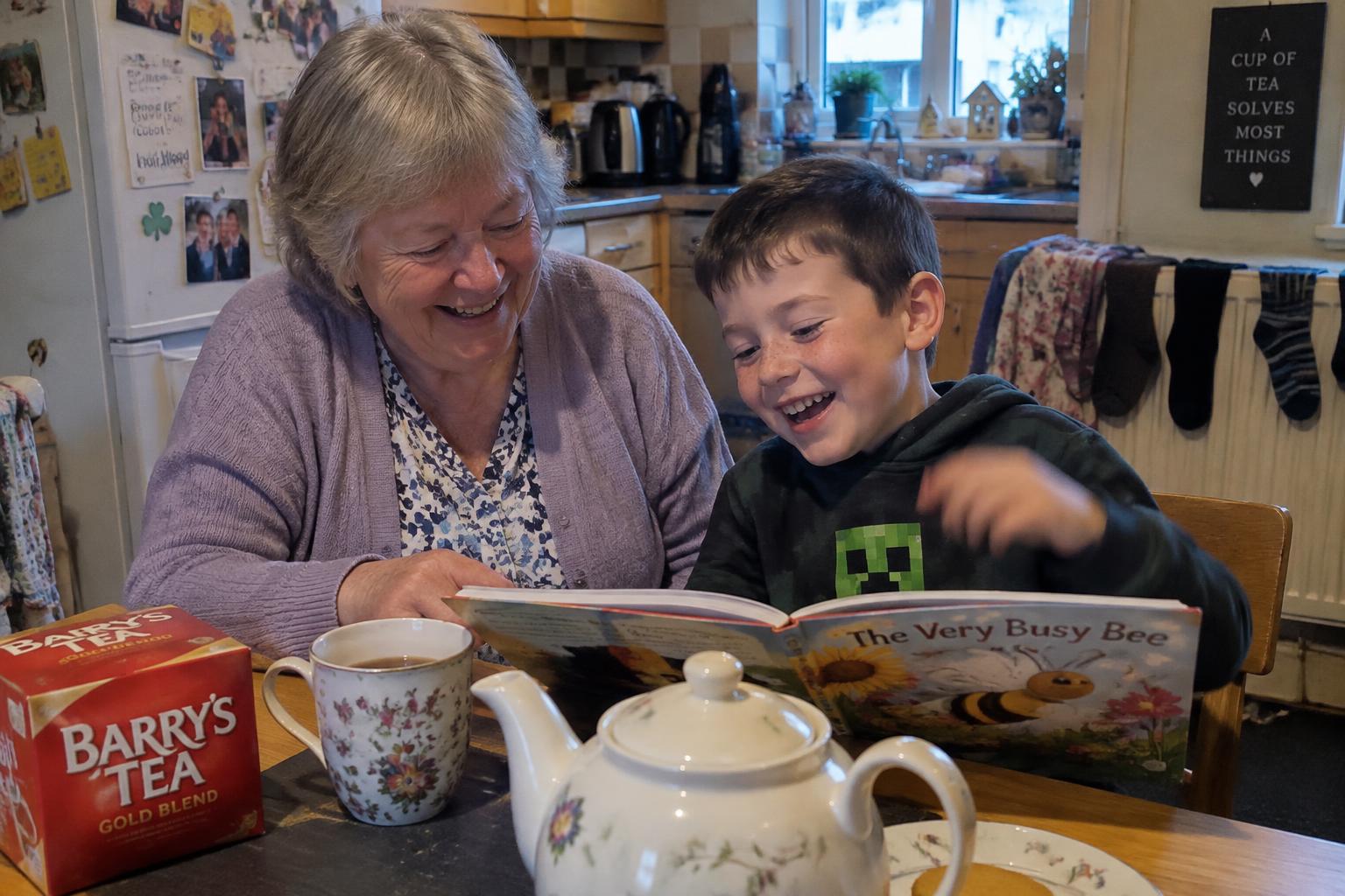 A granny and her grandson laughing over a picture book at the kitchen table, a pot of tea beside them